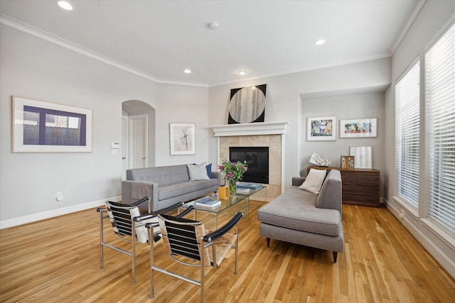 4005 Gramercy St, Houston, TX 77025 - living area featuring crown molding, light wood-style floors, arched walkways, a tile fireplace, and baseboards