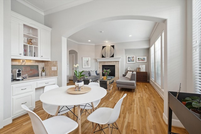 4005 Gramercy St, Houston, TX 77025 - dining room with arched walkways, a tile fireplace, light wood-style floors, crown molding, and recessed lighting