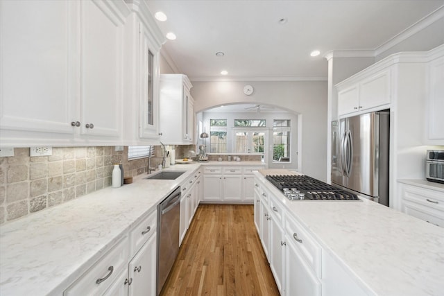 4005 Gramercy St, Houston, TX 77025 - kitchen featuring stainless steel appliances, a sink, white cabinetry, ornamental molding, and backsplash