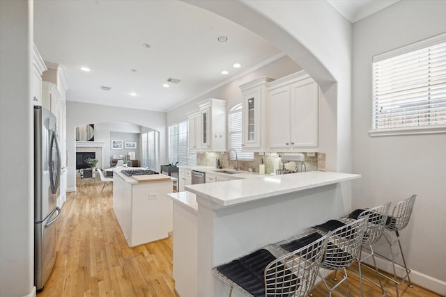 4005 Gramercy St, Houston, TX 77025 - kitchen featuring a sink, crown molding, appliances with stainless steel finishes, a peninsula, and a kitchen island