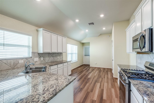 23745 Wood Green Terrace Dr, New Caney, TX 77357 - kitchen featuring stainless steel appliances, a sink, white cabinetry, vaulted ceiling, and recessed lighting