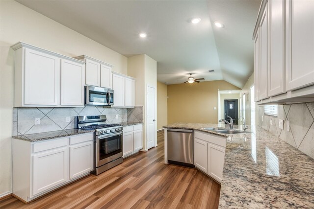 23745 Wood Green Terrace Dr, New Caney, TX 77357 - kitchen featuring stainless steel appliances, a sink, light wood-style floors, white cabinets, and ceiling fan
