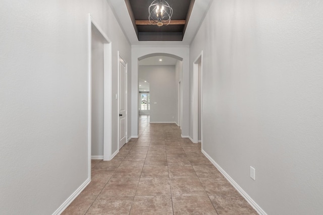 28437 Ofallon Mills Dr, Spring, TX 77386 - corridor with arched walkways, a tray ceiling, a chandelier, baseboards, and tile patterned floors
