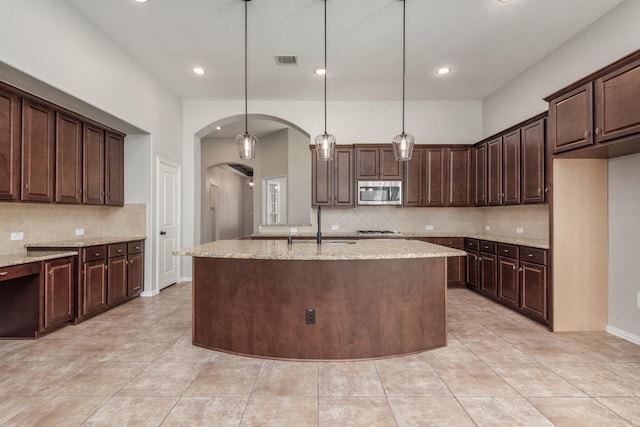 28437 Ofallon Mills Dr, Spring, TX 77386 - kitchen with stainless steel appliances, tasteful backsplash, arched walkways, dark brown cabinets, and recessed lighting