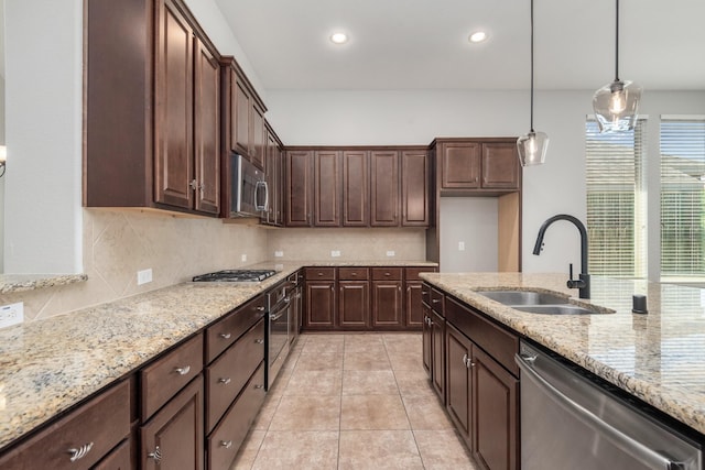 28437 Ofallon Mills Dr, Spring, TX 77386 - kitchen featuring a sink, stainless steel appliances, backsplash, light stone counters, and decorative light fixtures