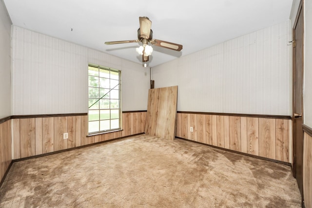 1417 Brigance Rd, Brazoria, TX 77422 - carpeted empty room with wood walls, wainscoting, and a ceiling fan
