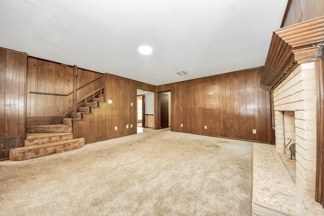 1417 Brigance Rd, Brazoria, TX 77422 - unfurnished living room with wooden walls, stairway, carpet, and a brick fireplace