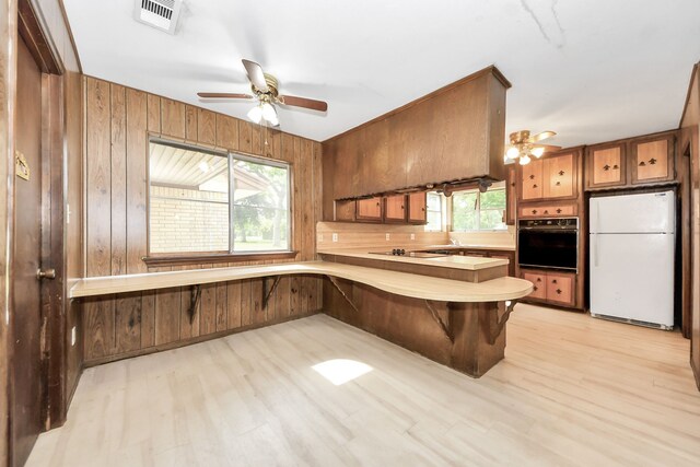 1417 Brigance Rd, Brazoria, TX 77422 - kitchen featuring black appliances, wooden walls, ceiling fan, light countertops, and a peninsula