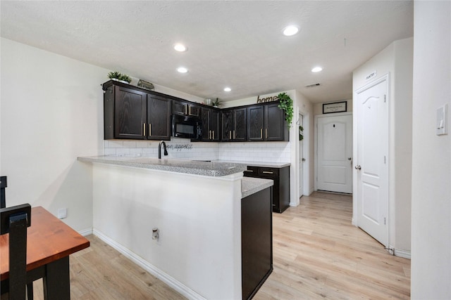 2814 Dustin Place Ct, Humble, TX 77396 - kitchen featuring black microwave, light wood finished floors, backsplash, a peninsula, and light countertops