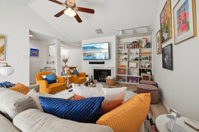 2829 Timmons Ln Unit 184, Houston, TX 77027 - living area with wood finished floors, a ceiling fan, a glass covered fireplace, lofted ceiling, and baseboards