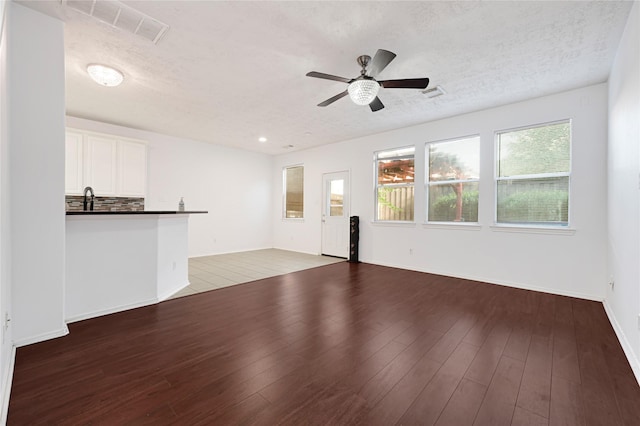 16106 Greenport Ln, Houston, TX 77084 - unfurnished living room featuring ceiling fan, a textured ceiling, wood finished floors, a sink, and baseboards