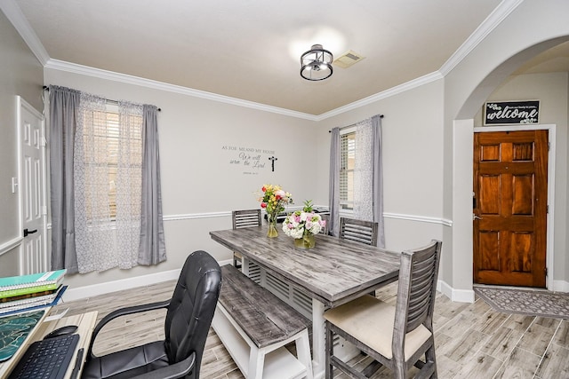 14720 Branchwest Dr, Houston, TX 77082 - dining space with crown molding, arched walkways, light wood finished floors, and baseboards