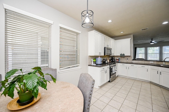 14720 Branchwest Dr, Houston, TX 77082 - kitchen with appliances with stainless steel finishes, decorative backsplash, dark countertops, light tile patterned floors, and white cabinets
