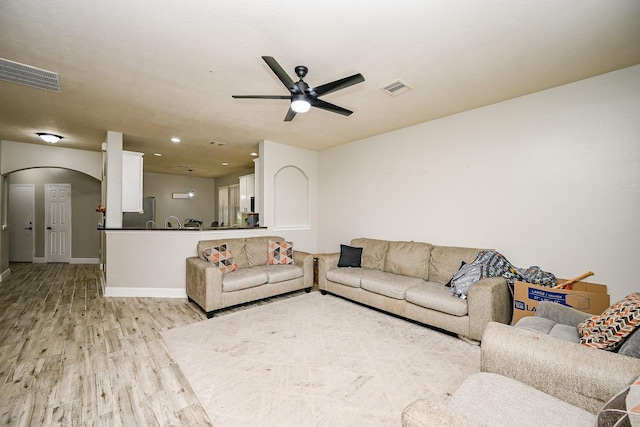14720 Branchwest Dr, Houston, TX 77082 - living room featuring arched walkways, light wood finished floors, ceiling fan, baseboards, and recessed lighting