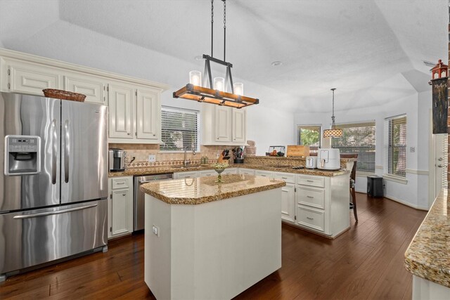 44 Westchester Dr, Conroe, TX 77304 - kitchen featuring appliances with stainless steel finishes, a peninsula, dark wood-type flooring, decorative backsplash, and lofted ceiling