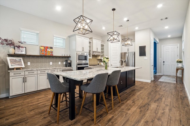 10407 Quiet Courtyard Rd, Houston, TX 77043 - kitchen with stainless steel appliances, decorative backsplash, dark wood-type flooring, an island with sink, and recessed lighting