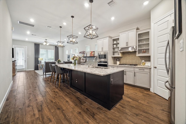 10407 Quiet Courtyard Rd, Houston, TX 77043 - kitchen with appliances with stainless steel finishes, dark wood-type flooring, a spacious island, a breakfast bar area, and backsplash