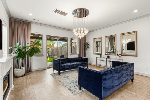 living room with baseboards, light wood-style flooring, recessed lighting, a chandelier, and a glass covered fireplace