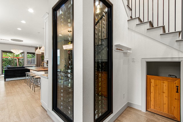 wine area featuring wood finished floors, recessed lighting, a textured wall, and baseboards