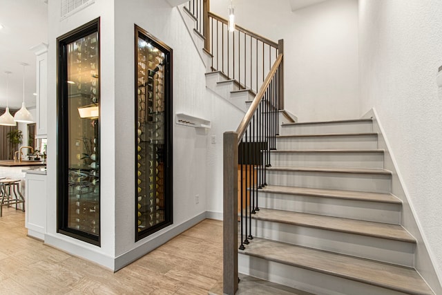 stairs with wood finished floors and a towering ceiling