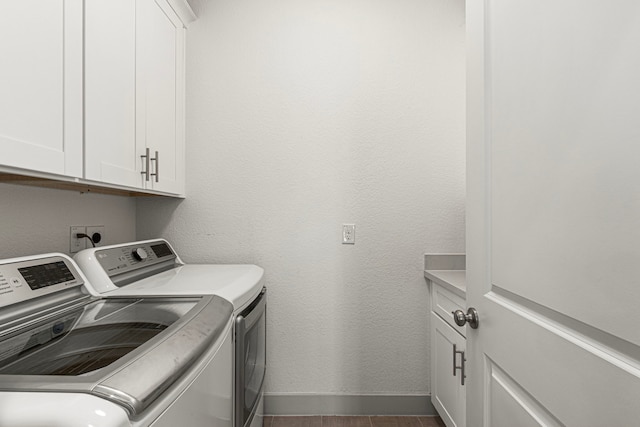 laundry area with independent washer and dryer, cabinet space, baseboards, and dark wood-style floors