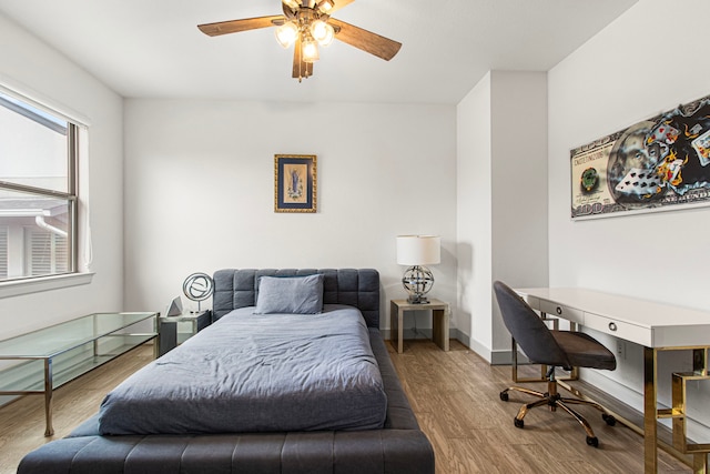 bedroom featuring wood finished floors, ceiling fan, and an office area