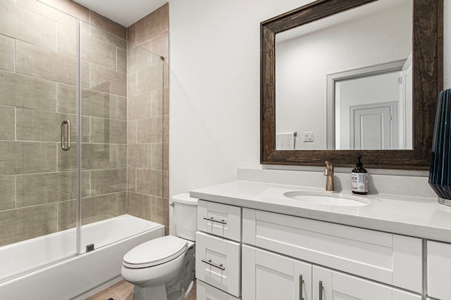 bathroom featuring toilet, vanity, and bath / shower combo with glass door