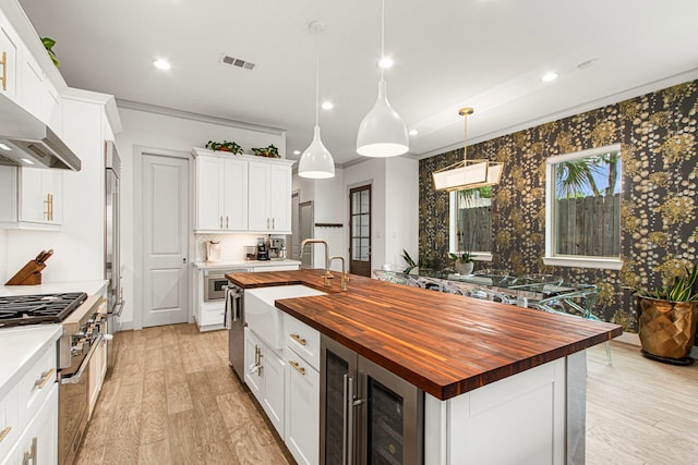 kitchen featuring butcher block countertops, a sink, beverage cooler, recessed lighting, and tasteful backsplash