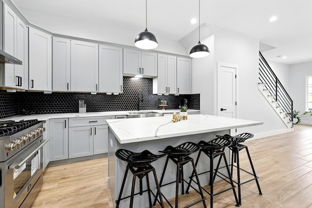 5209 Canal St, Houston, TX 77011 - kitchen with stainless steel stove, a sink, light stone countertops, tasteful backsplash, and a breakfast bar