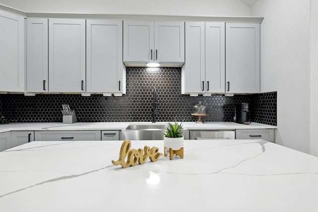 5209 Canal St, Houston, TX 77011 - kitchen with a sink, backsplash, light stone countertops, and gray cabinetry