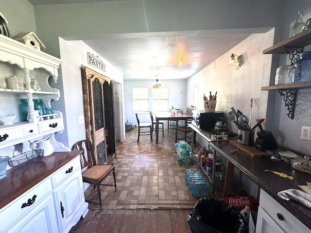 12215 Fm 442nd Rd, Boling, TX 77420 - kitchen with open shelves, dark countertops, white cabinetry, a textured ceiling, and brick patterned floors