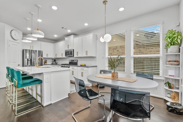 2824 Jehlon Ln, Conroe, TX 77385 - kitchen featuring appliances with stainless steel finishes, a sink, dark wood-type flooring, white cabinetry, and a center island with sink