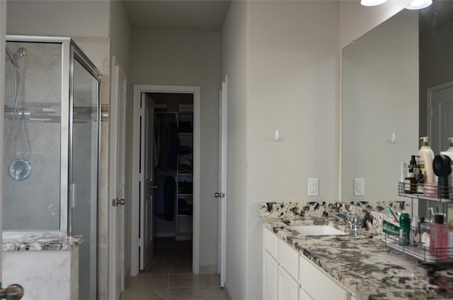 bathroom with a shower stall, a walk in closet, tile patterned floors, and vanity