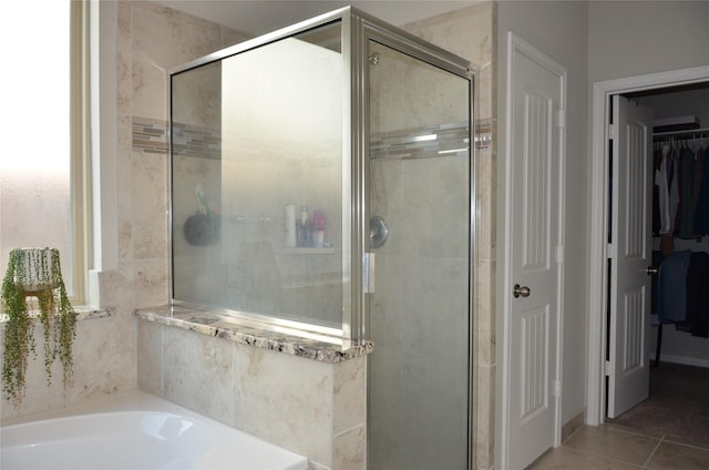 full bathroom with a stall shower, a garden tub, tile patterned floors, and a spacious closet