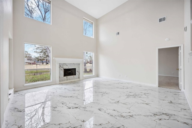 1910 Shark Ct, Crosby, TX 77532 - unfurnished living room with a high ceiling, marble tiled floors, a high end fireplace, and baseboards