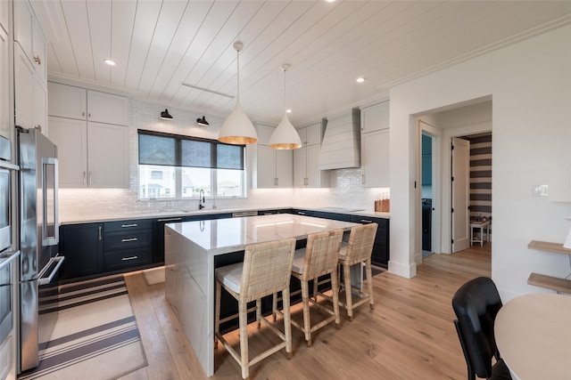 1311 Oahu Dr, Tiki Island, TX 77554 - kitchen featuring custom range hood, a breakfast bar area, light wood-style floors, high quality fridge, and a center island