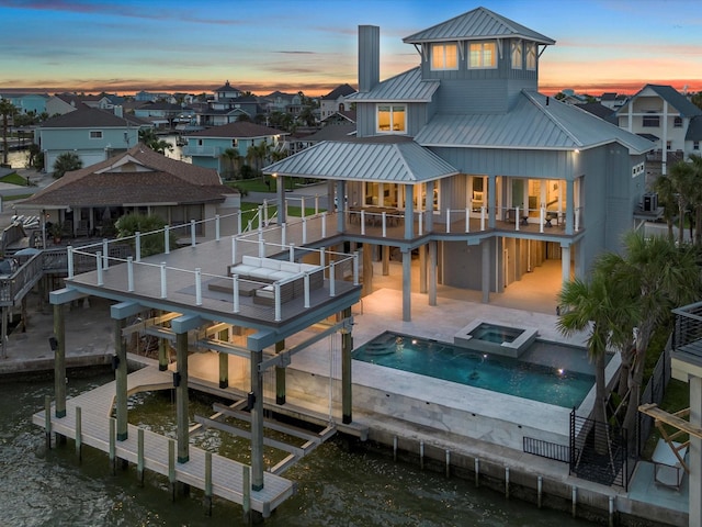 1311 Oahu Dr, Tiki Island, TX 77554 - rear view of house featuring a standing seam roof, metal roof, a water view, a balcony, and boat lift