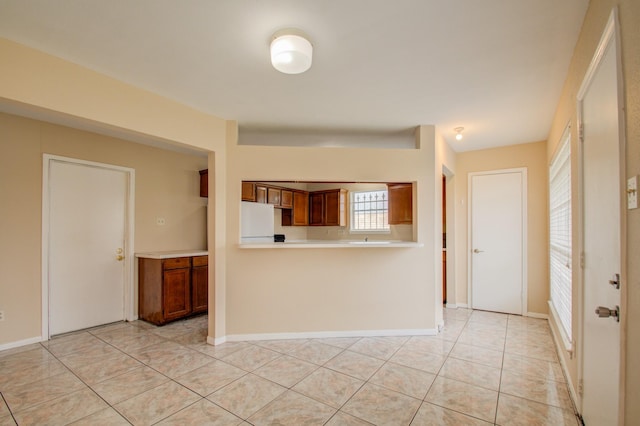 9470 Gulf Bridge St, Houston, TX 77075 - kitchen featuring light countertops, freestanding refrigerator, light tile patterned floors, brown cabinets, and baseboards