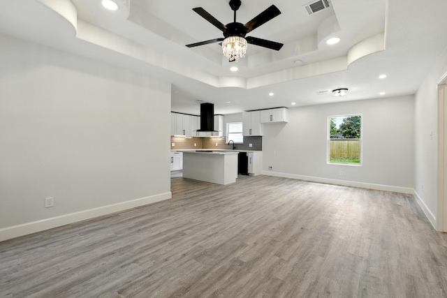 5614 Northridge Dr, Houston, TX 77033 - unfurnished living room featuring a raised ceiling, recessed lighting, light wood-type flooring, a sink, and ceiling fan