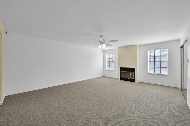 9850 Pagewood Ln Unit 1208, Houston, TX 77042 - unfurnished living room featuring a ceiling fan, a fireplace with flush hearth, light colored carpet, and baseboards