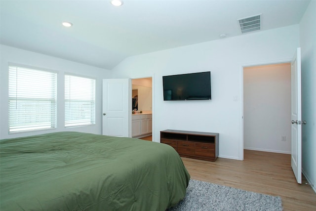 bedroom featuring light wood finished floors, baseboards, lofted ceiling, recessed lighting, and ensuite bathroom