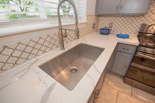 2030 Cutter Dr, League City, TX 77573 - kitchen view of gray cabinets, a sink, tasteful backsplash, range with two ovens, and light stone counters