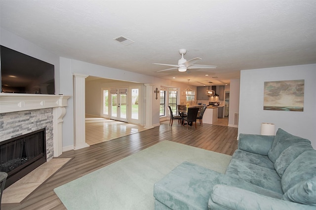 2030 Cutter Dr, League City, TX 77573 - living area featuring french doors, light wood-type flooring, a stone fireplace, a ceiling fan, and baseboards