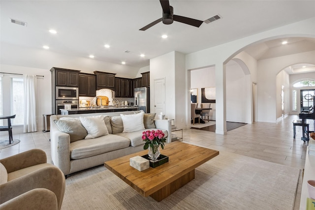 living room with a ceiling fan, arched walkways, recessed lighting, baseboards, and light tile patterned flooring