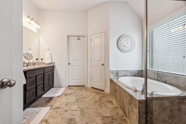 bathroom featuring a bath, vanity, and lofted ceiling