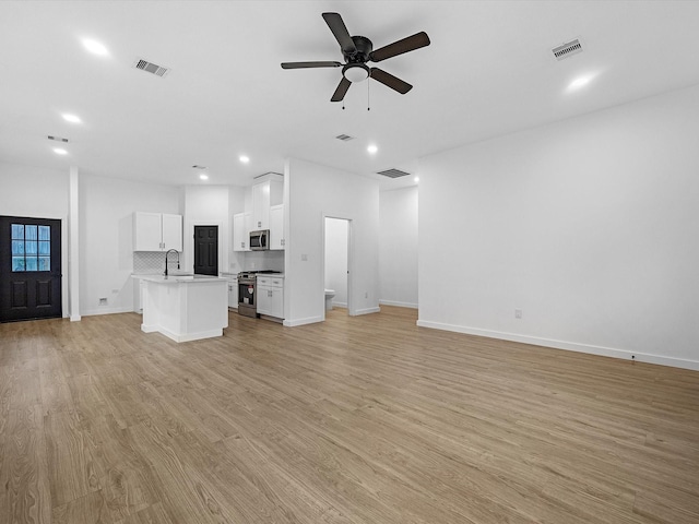 unfurnished living room with a ceiling fan, recessed lighting, light wood-type flooring, baseboards, and a sink