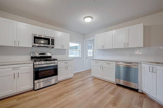 103 Anna St, Tomball, TX 77375 - kitchen featuring stainless steel appliances, tasteful backsplash, light wood-type flooring, and white cabinets