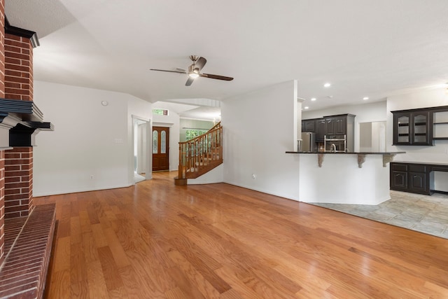 19906 Bayberry Creek Dr, Magnolia, TX 77355 - unfurnished living room featuring a fireplace, light wood-style floors, ceiling fan, stairway, and recessed lighting