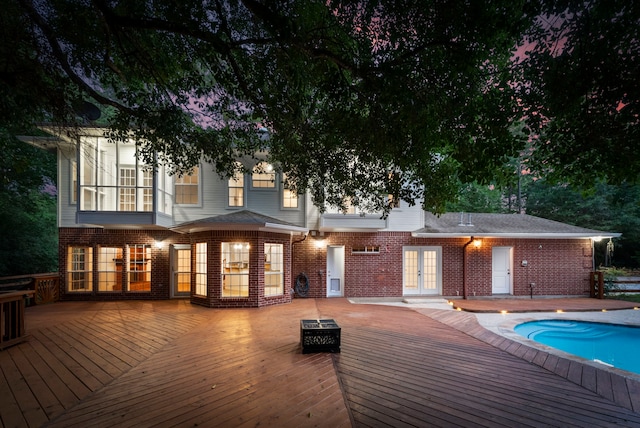 19906 Bayberry Creek Dr, Magnolia, TX 77355 - rear view of house with french doors, a wooden deck, an outdoor pool, and brick siding