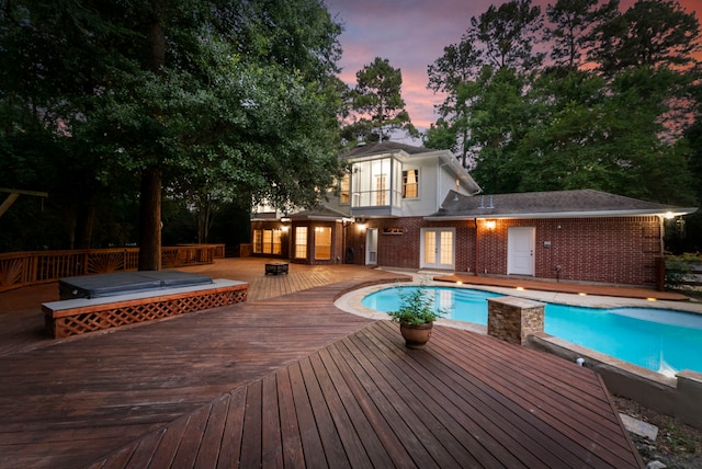 19906 Bayberry Creek Dr, Magnolia, TX 77355 - pool at dusk with french doors, a wooden deck, and an outdoor pool